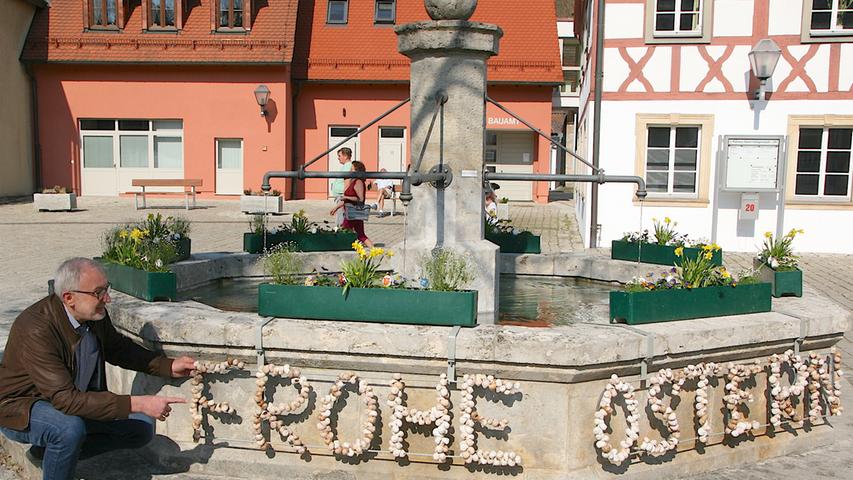 In Heiligenstadt freut sich Bürgermeister Helmut Krämer, dass der Marktplatzbrunnen doch nicht ganz kahl geblieben ist. Der FSV-Vorsitzende Roland Hohe hat für Blumen gesorgt und vom Schmuckteam hat Renate Bärnreuther das schneckige "Frohe Ostern" neu gefasst.