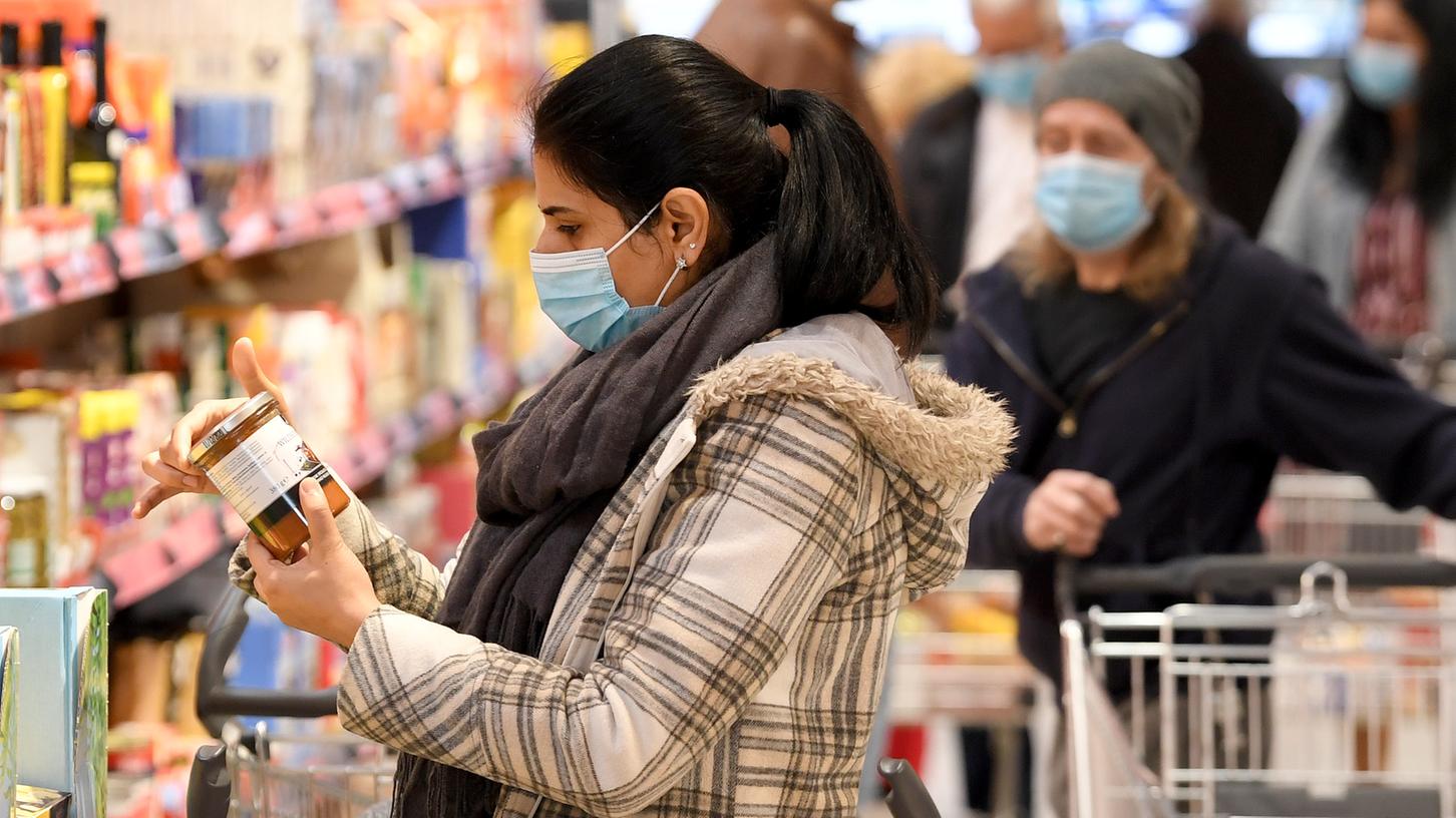 Eine Frau geht mit Mundschutz einkaufen. Viele Helfer besorgen Lebensmittel für Menschen aus der Risikogruppe