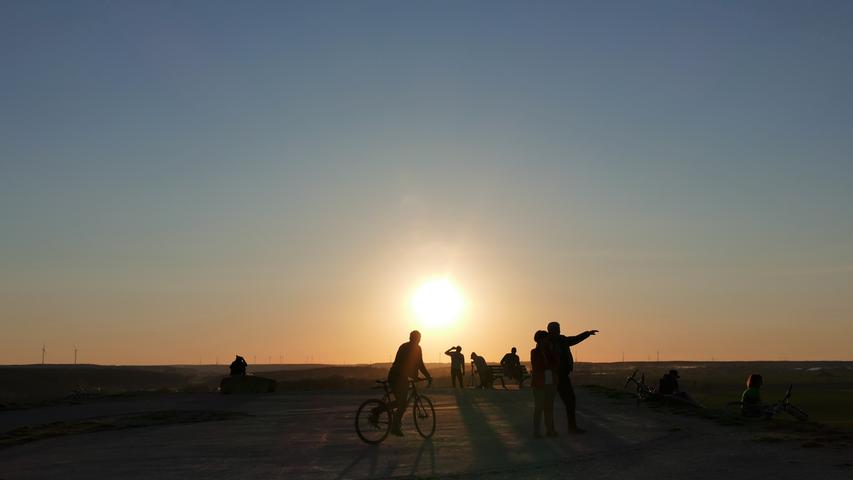 Im Sonnenuntergang genießen Menschen den Ausblick vom Fürther Solarberg