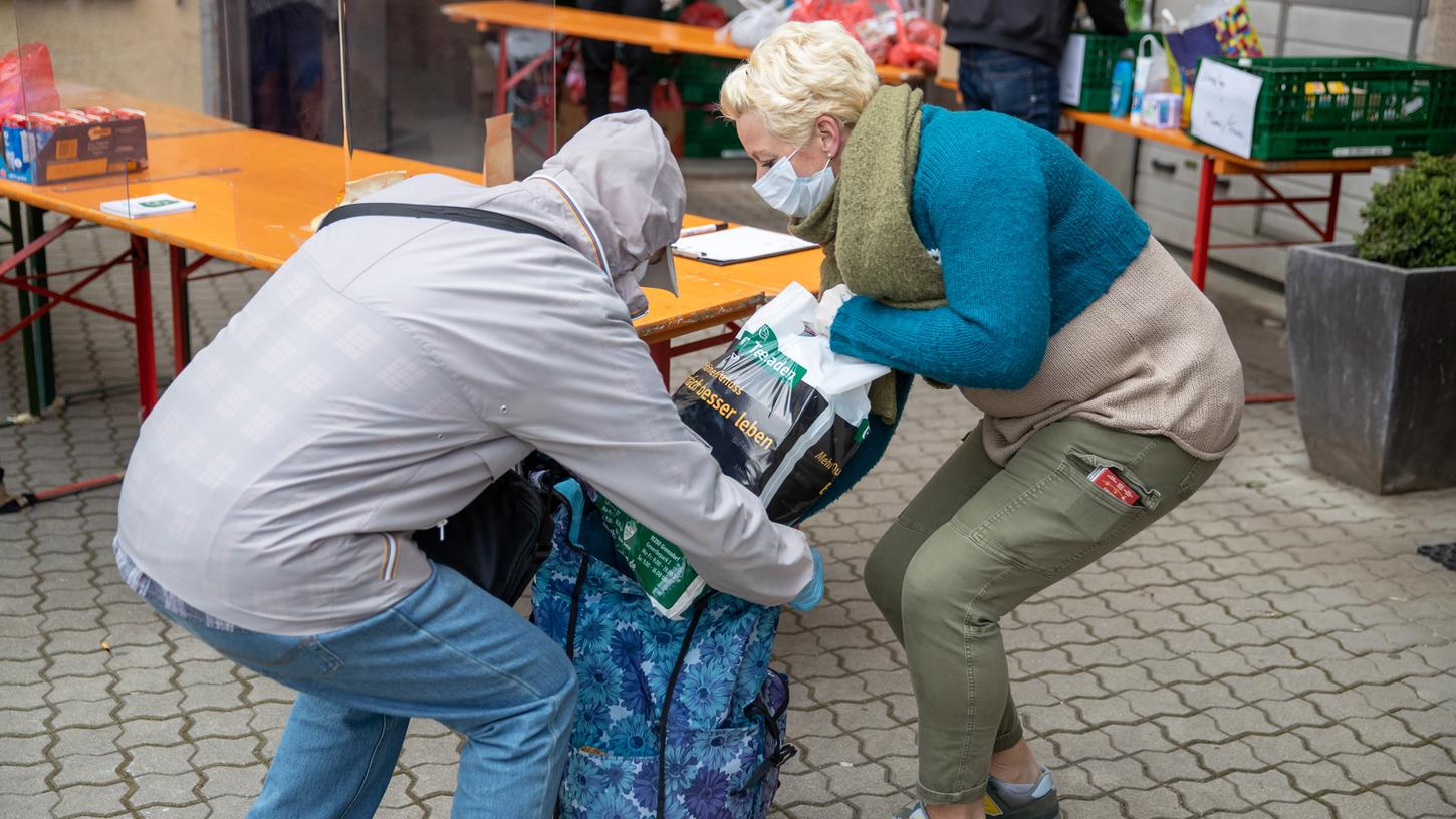 Susa (r), eine Helferin der Initiative "Fürther sind solidarisch", packt bei der "alternativen Tafel" einem Bürger Hygieneartikel in die Tasche.