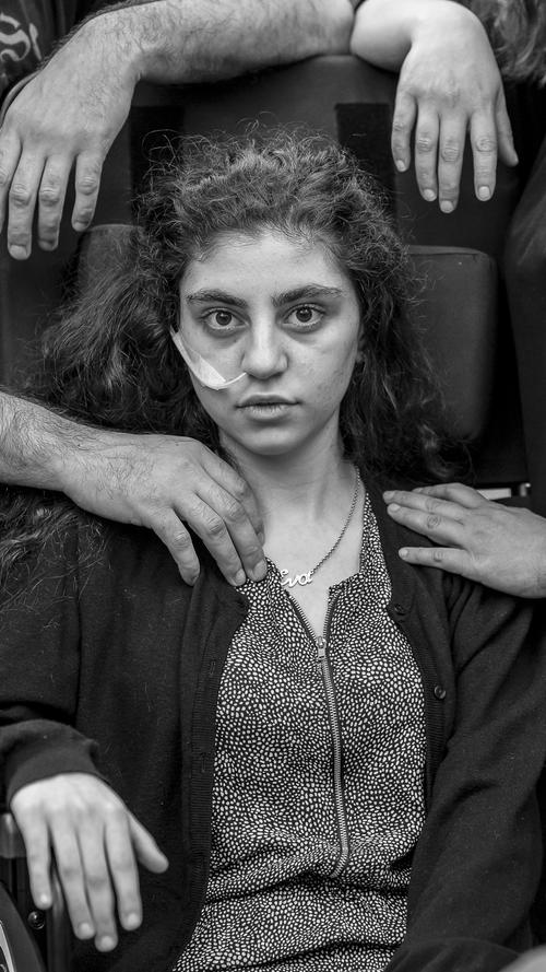 Dieses Bild namens "Awakening" (Erwachen), aufgenommen von Tomek Kaczor, zeigt ein 15-jähriges armenisches Mädchen, das kürzlich aus einem durch das Resignationssyndrom verursachten katatonischen Zustand erwacht ist. Es sitzt in einem Flüchtlingslager auf einem Rollstuhl, flankiert von seinen Eltern. Die Jury sprach diesem Foto den 1. Preis in der Kategorie "Porträt" zu.