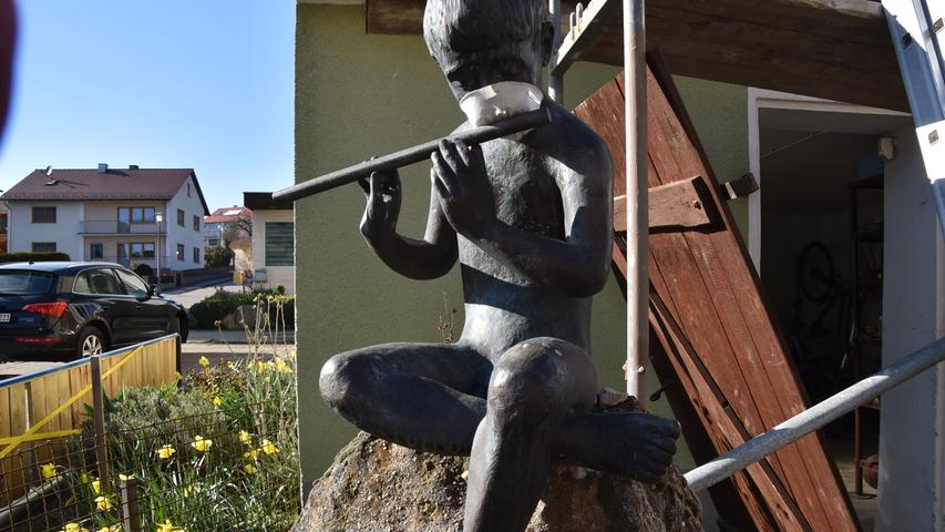 Als kleine Aufmunterung gedacht ist die mit einem Mundschutz versehene Skulptur des Flötenspielers in einem Anwesen in Ebenried. Daran sollten wir uns zum gegenseitigen Schutz gegen Corona gewöhnen.