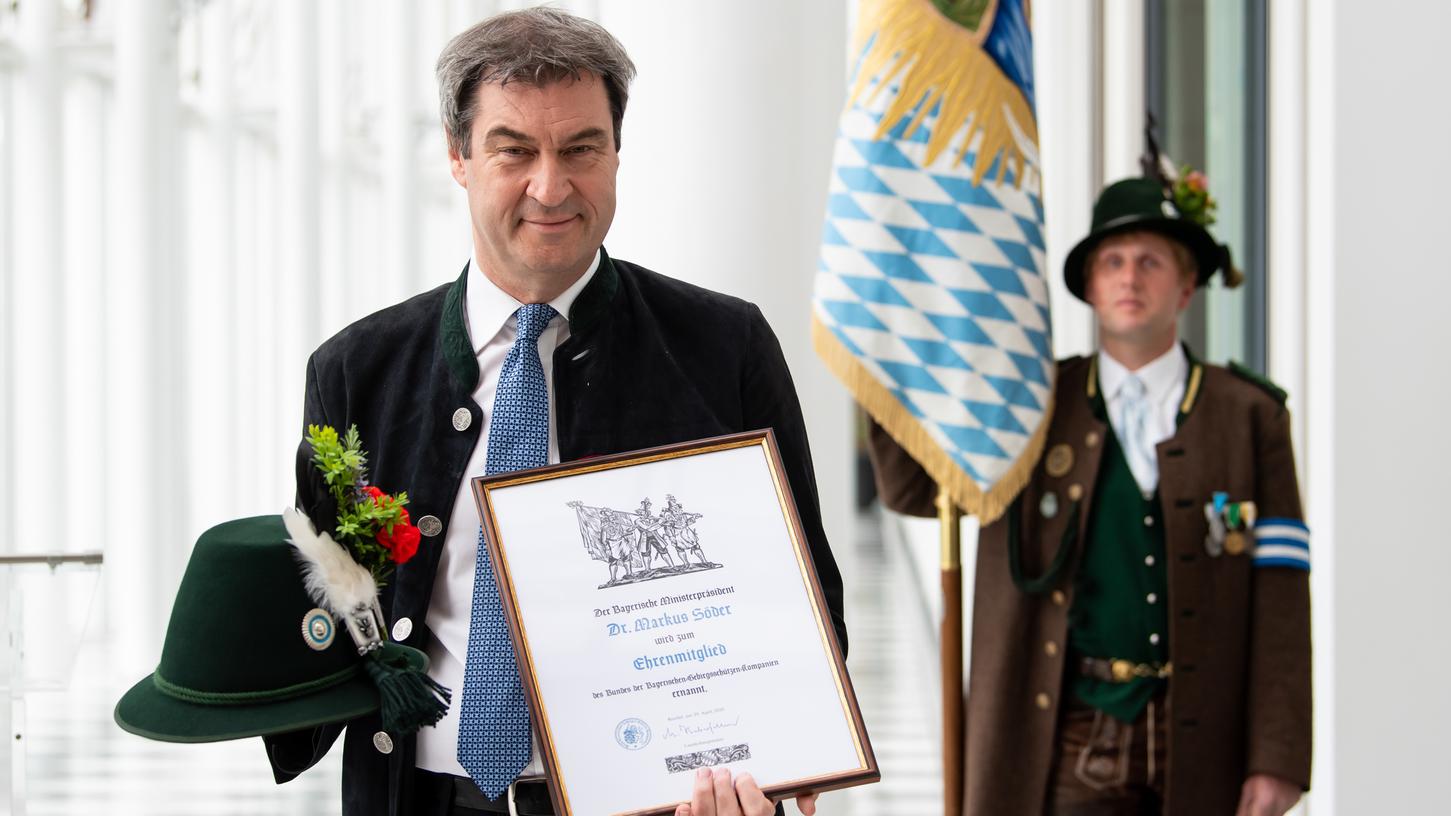 Markus Söder (l, CSU), Ministerpräsident von Bayern, hält eine Ernennungsurkunde und einen Schützenhut der bayerischen Gebirgsschützen in den Händen. Söder wurde am Mittwoch von einer Delegation zum Ehrenmitglied der Gebirgsschützen ernannt.