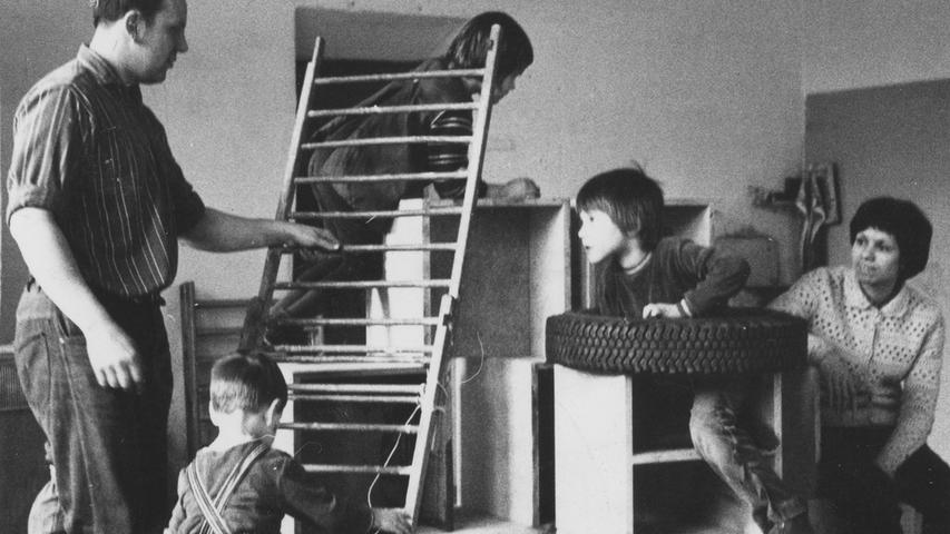 Leiter, Kästen, Autoreifen und sogar die alte Schreibmaschine gehören zum Spielzeug im antiautoritären Kinderladen. Ein Vater (links) und eine junge Mutter (rechts) lassen ihre Sprößlinge gewähren. Hier geht es zum Artikel vom 6. Mai 1970: Verbote sind verboten