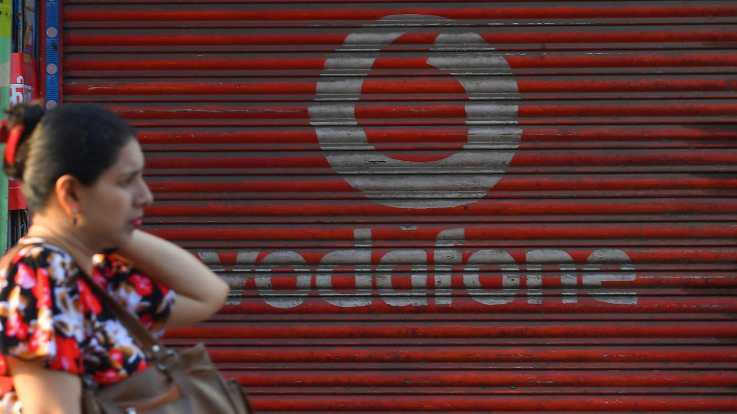 Eine Frau geht an einem Logo des Vodafone-Konzerns vorbei.