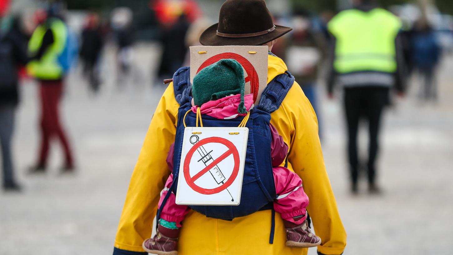 Eine Teilnehmerin einer Protestkundgebung der Initiative "Querdenken" trägt auf dem Cannstatter Wasen ein Schild gegen Impfungen auf ihrem Rücken.