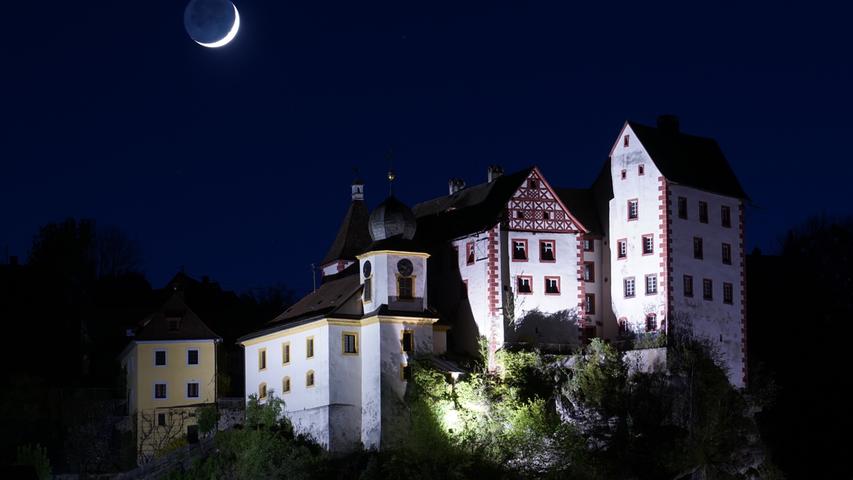 Die Mondsichel und Burg Egloffstein ziehen in der Nacht die Blicke auf sich.