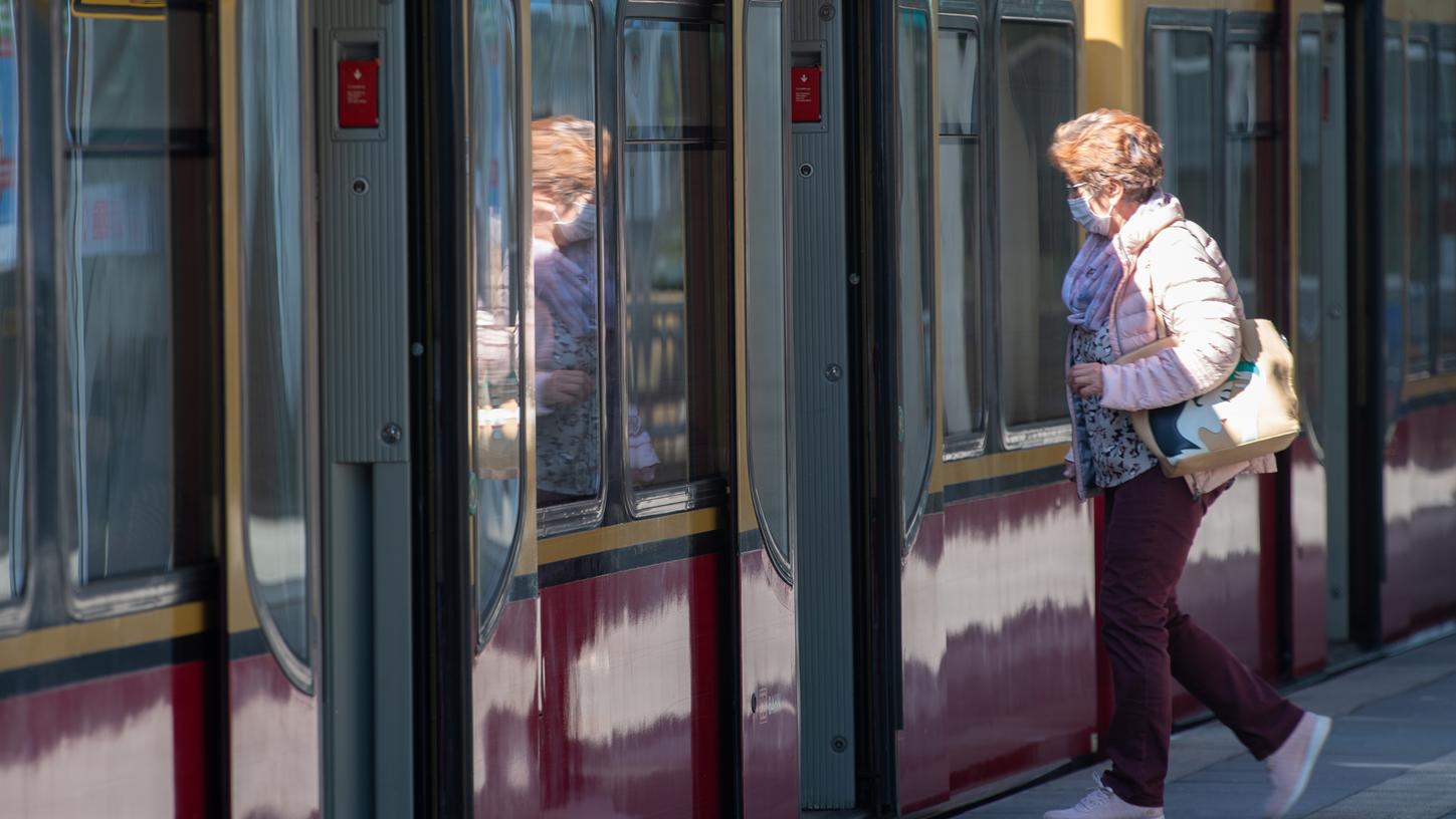 Eine Frau mit Mundschutz steigt in eine S-Bahn: Wegen der Corona-Pandemie bleiben im ÖPNV viele Sitzplätze leer, die Fahrgastzahlen sind deutlich zurückgegangen.