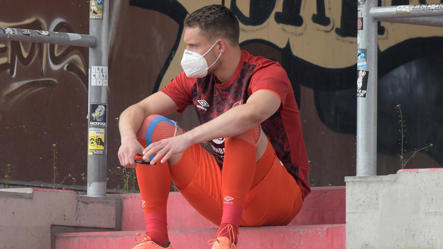 Christian Mathenia sitzt nach seiner Roten Karte mit Maske auf der Tribüne des Millerntor-Stadions.