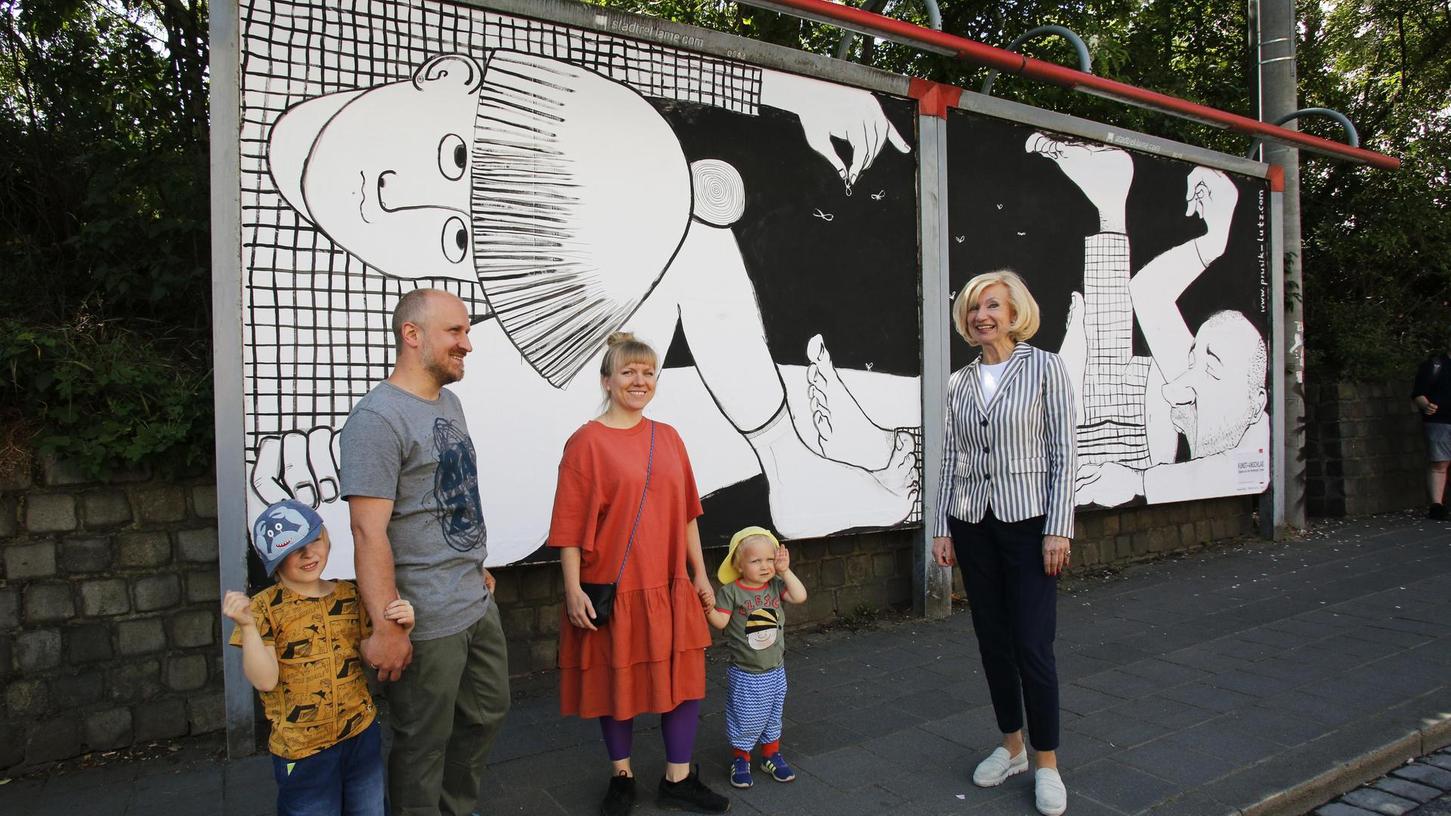 Corona engt uns ein: Den aktuellen Alltag hat das Künstlerpaar Kasia und Olaf Prusik-Lutz (hier mit seinen Kindern und Kulturbürgermeisterin Julia Lehner) auf einer Plakatwand in der Bahnhofstraße illustriert. Weitere Künstlerinnen und Künstler haben ebenfalls Plakatflächen der Stadtreklame in Nürnberg gestaltet.