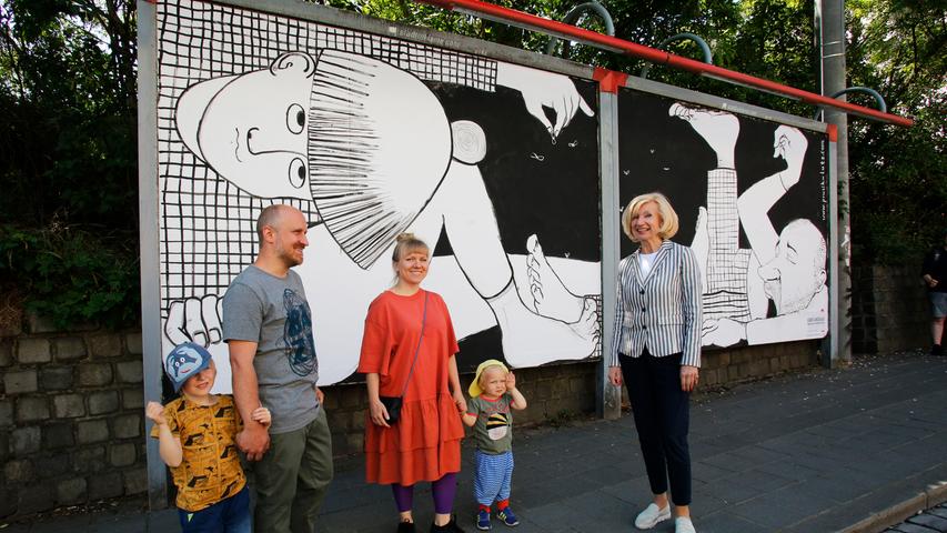 Das Künstlerpaar Kasia & Olaf Prusik-Lutz mit seinen Kindern und Nürnbergs Kulturbürgermeisterin Julia Lehner vor seiner Plakatarbeit am Marientunnel.