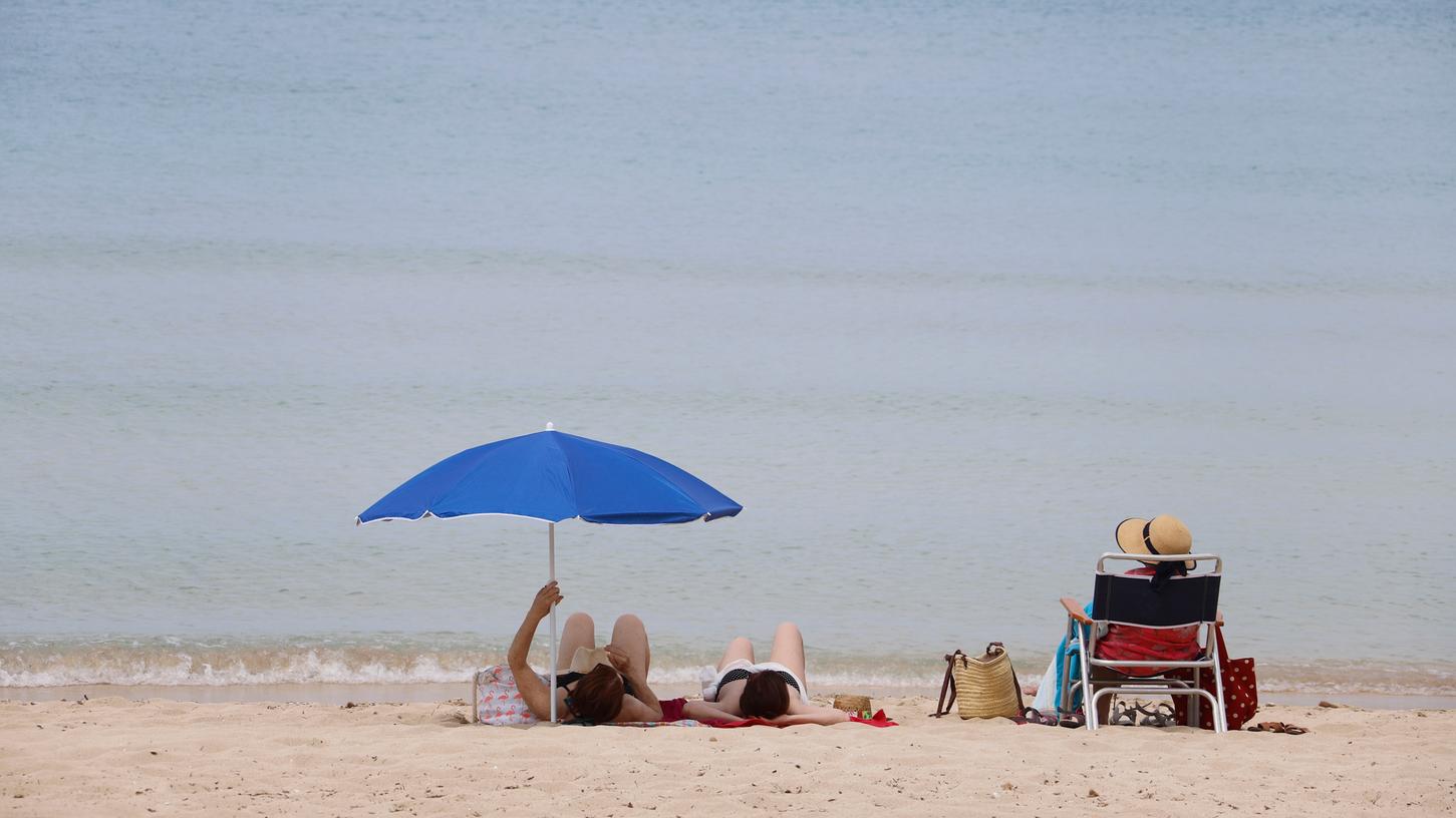 Spanien, Palma de Mallorca: Menschen sonnen sich am Strand von Arenal. Nach einer mehr als zweimonatigen Zwangsschließung wegen der Corona-Pandemie haben die Urlaubsinsel und viele andere Regionen Spaniens am Montag ihre Strände wieder geöffnet.