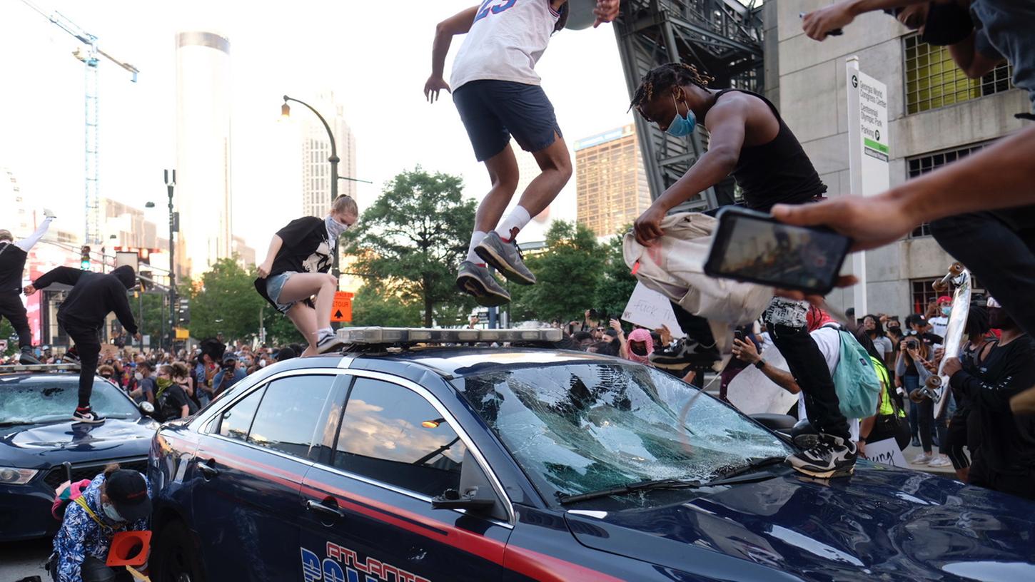 Demonstranten klettern vor einem Firmengebäude des Senders CNN auf ein Auto der Polizei. Der Protest richtet sich nach dem gewaltsamen Tod des Afroamerikaners Floyd gegen Rassismus und Polizeigewalt.