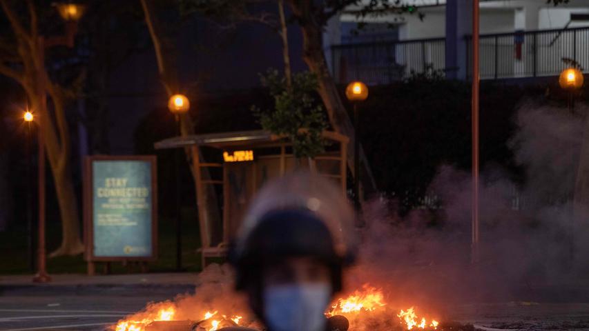A Police officer is seen in front a trash on fire in Downtown Los Angeles on May 30, 2020 during a protest against the death of George Floyd, an unarmed black man who died while while being arrested and pinned to the ground by the knee of a Minneapolis police officer. - Clashes broke out and major cities imposed curfews as America began another night of unrest Saturday with angry demonstrators ignoring warnings from President Donald Trump that his government would stop violent protests over police brutality cold. (Photo by Apu GOMES / AFP)