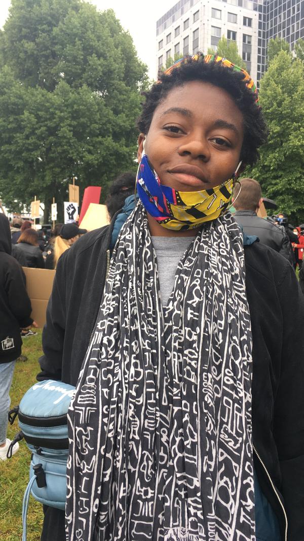 "Ich bin überwältigt von der Anzahl der Besucher auf dieser Demo. Das erlebe ich in diesem Umfang zum ersten Mal, obwohl ich schon oft auf Demonstrationen war, zum Beispiel gegen Pegida. Ich bin Musikerin und unterstütze in Nürnberg den Verein "AfroDeutsche". Wir veranstalten zum Beispiel jährlich ein Fest auf dem Nürnberger Jakobsplatz, wo wir afrikanischen Gospel spielen. Ich bin in Deutschland geboren, meine Eltern stammen aus der Demokratischen Republik Kongo und aus Angola. Wir haben mehrmals Rassismus selbst erfahren, aber meine Eltern haben mir beigebracht, mich nicht auf das Schlimme, sondern auf die guten Erlebnisse zu fokussieren. Aktuell erleben wir eine Veränderung, weil so viele Menschen aufstehen für Wandel und Kommunikation miteinander. Die Demos sorgen dafür, dass die Menschen zuhören und sie schaffen den nötigen Druck für Veränderungen. Friedliche Demos wie hier sind dabei der richtige Weg."
