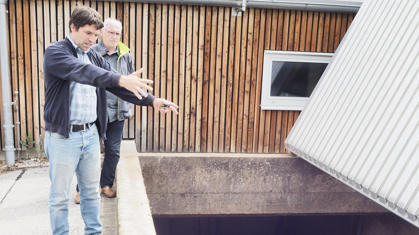 Fabian Röhnisch (vorne) und Alfred Maderer von der FBG stehen vor dem Hackschnitzelbunker der Anlage. Im Sommer sorgt ein Gasbrennkessel für Wärme.