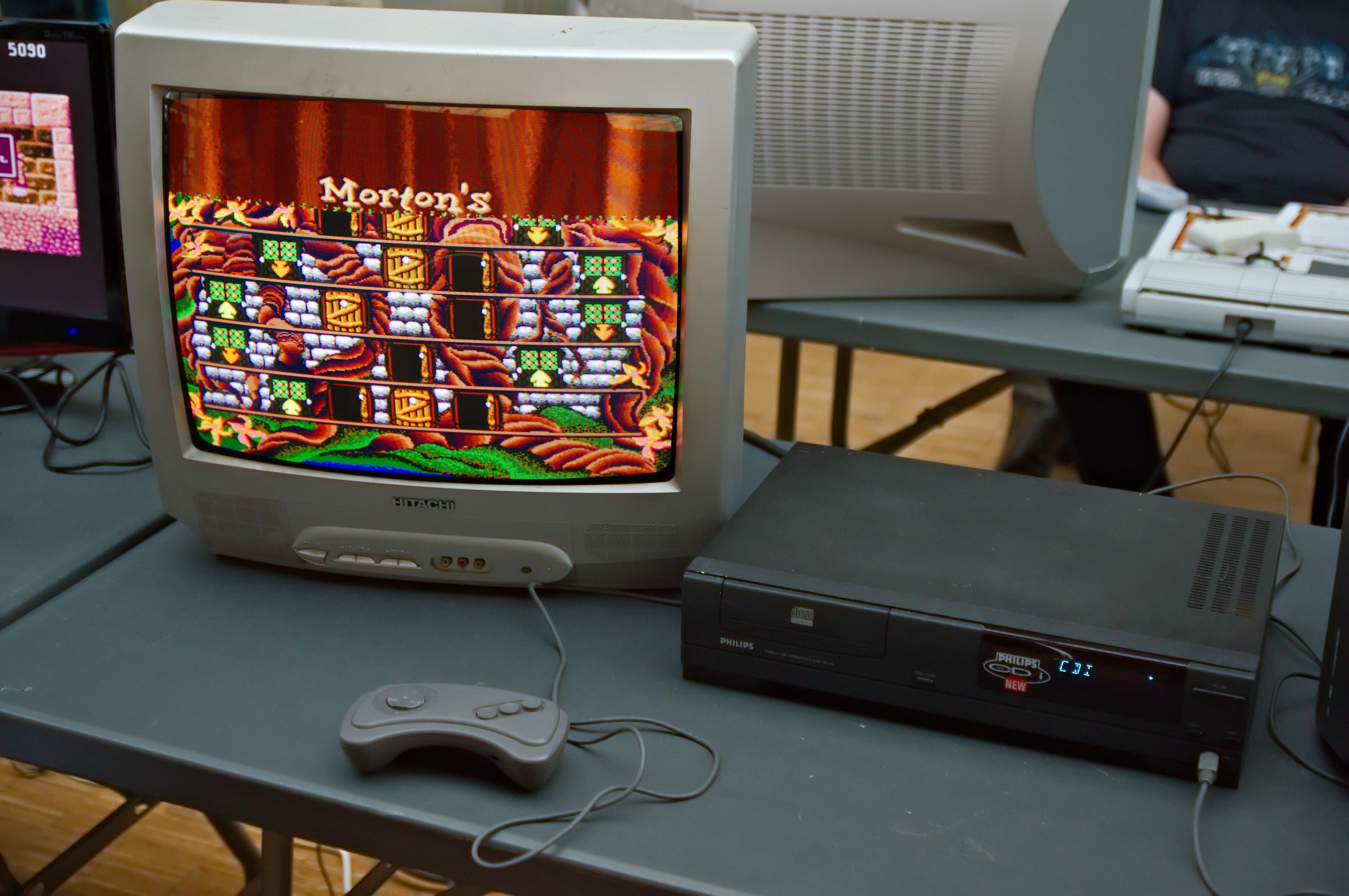 Während die meisten Konsolen noch auf Spielmodule setzen, geht Philips 1991 in Kooperation mit Sony einen anderen Weg – und veröffentlicht mit dem CD-i eine Konsole, die das damals neue Format der CDs nutzt. Was sich in den Stereoanlagen später als Erfolg herausstellen sollte, floppt als Spielekonsole aber völlig. Weniger als 600.000 Einheiten des CD-i werden verkauft – doch Sony, zu diesem Zeitpunkt ein renommierter Elektronikkonzern aus Japan, hat trotz des Misserfolgs Blut geleckt,…