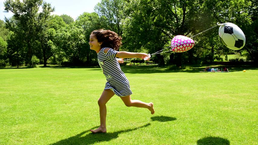 Viele Fürtherinnen und Fürther nutzen das hochsommerliche Wetter, um draußen zu spielen und zu toben oder einfach nur um Freunde zu treffen und zu entspannen - so wie die neunjährige Delschin mit ihren Ballons im Stadtpark.