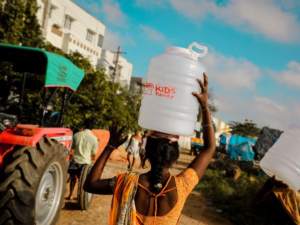 Eine Frau trägt einen Behälter mit Trinkwasser im Ramamurthy Nagar Slum in Bangalore (Indien); das Nürnberger Unternehmen Hemmersbach ist dort mit seinem humanitären Projekt Kids Family vor Ort, gibt sauberes Wasser aus und betreut u.a. Straßenkinder.