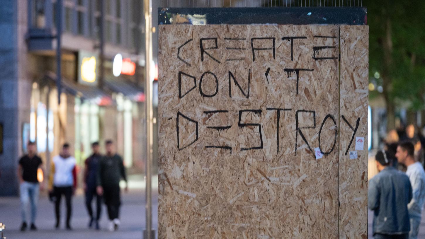"Create don't destroy" (Erschaffe, zerstöre nicht): Dieser Spruch steht auf Holzplatten, die eine in der Gewaltnacht zerstörte Scheibe in der Stuttgarter Innenstadt abdecken.