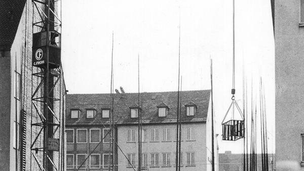 In den 1960er Jahren machte der Neubau in der Karolinenstraße 6 in der Nachbarschaft von Nassauer Haus und später Karstadt (dahinter) Probleme: "Eine Lücke an herausragender Stelle wird bald geschlossen", hieß es damals in den Nürnberger Nachrichten. Allerdings gab es dabei technische Probleme an "prominenter" Ecke: Ein ebenerdiges Gebäude trennte den Kran von der Baustelle. Der Kran durfte, weil es die Bauordnungsbehörde so vorschrieb, nicht über diesen Bau schwenken, weil etwas herunterfallen könnte. Er musste also wegen der gesamten Bauarbeiten einen Bogen beschreiben, um seine Last über das überdachte Kehrumgässchen (re.) hinweg zu transportieren.