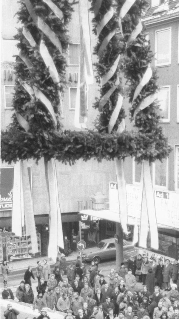 Dieses Foto zeigt die Richtkrone und die Zuschauer beim damaligen Richtfest. Die Bildunterschrift in der Zeitung besagte: "Die schwierige Geburt für den Neubau der Karstadt AG im Herzen von Nürnberg geht ihrem Ende entgegen: nach 13 Monaten Bauzeit wurde gestern das Richtfest gefeiert. Im Herbst soll der Gebäudekomplex zwischen Adler-, König- und Karolinenstraße seiner Bestimmung übergeben werden."