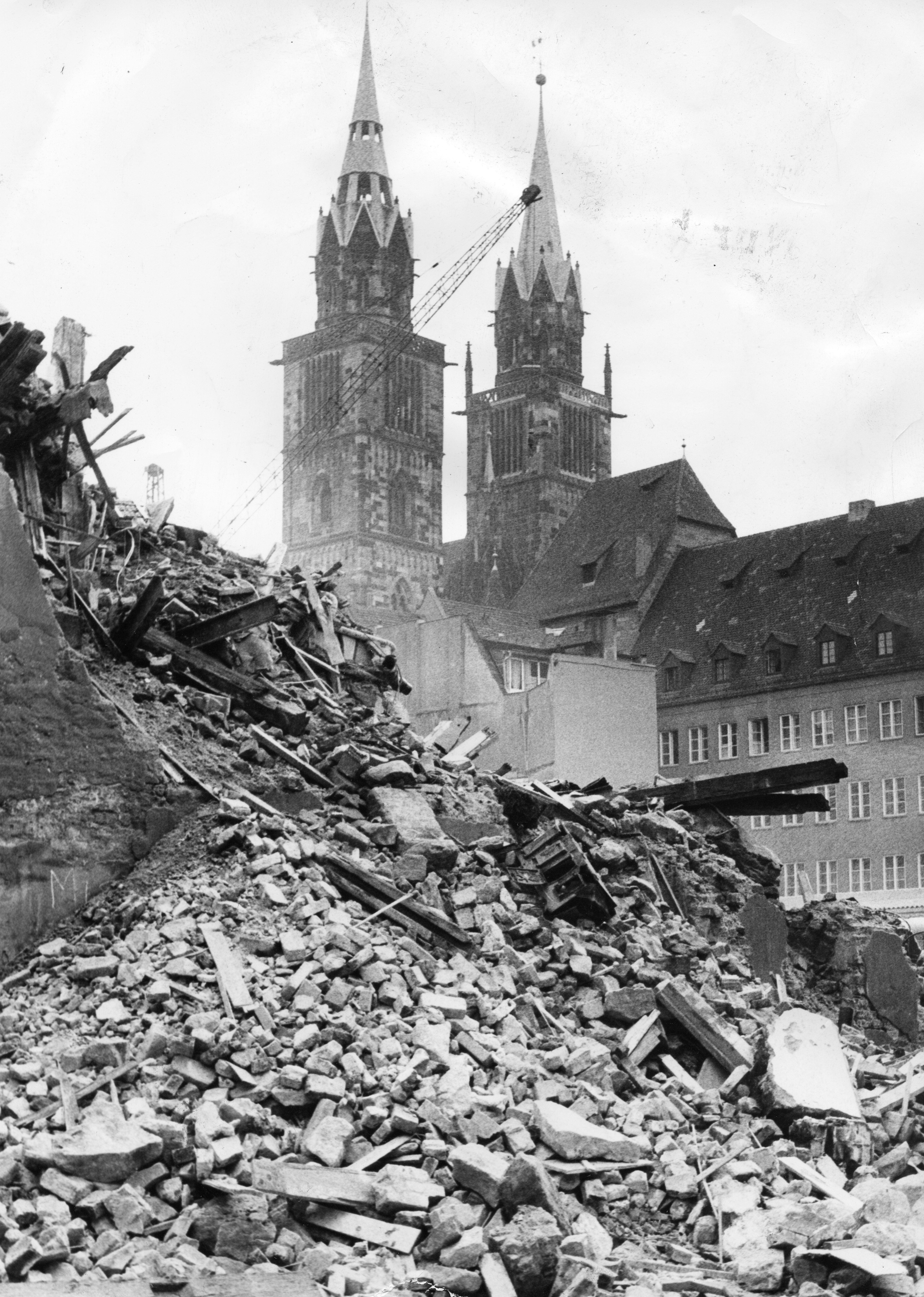 Diese Aufnahme vom Areal für das zukünftige Karstadt-Gebäude erschien in den Nürnberger Nachrichten am 3. September 1970, also noch Jahre vor dem Abschluss des Bauprojekts. Die damalige Überschift des Artikels lautete "Abbruch unter den Lorenz-Türmen". Unter dem Bild stand damals geschrieben: "Neues Leben blüht aus den Ruinen; wo es jetzt aussieht wie nach einem Bombenangriff, soll Nürnbergs erstes Kaufhaus mit direktem U-Bahn-Anschluß entstehen. Auf dem Gelände zwischen der Karolinenstraße, dem Hörmannsgäßchen, der Adlerstraße und der Königstraße plant die Karstadt-AG ein mehrstöckiges Warenhaus. Deshalb sind die früheren Gebäude der Dresdner Bank dem Abbruchhammer verfallen. Während von den rückwärtigen Gebäuden nur noch einige Wände stehen, soll der vordere Bauteil an der Karolinenstraße noch stehen bleiben, damit sich dem Dürer-Jahr hier nicht eine häßliche Baulücke bietet. Nach 1971 soll auch erst mit den Arbeiten an der U-Bahn-Haltestelle in diesem Bereich begonnen werden, ehe anschließend der Bau des Kaufhauses in Angriff genommen werden kann. Dem Neubau weichen muß übrigens auch das Nachtlokal im Hörmannsgäßchen."