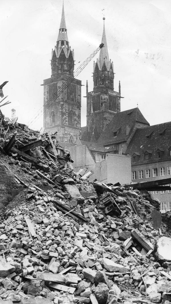 Diese Aufnahme vom Areal für das zukünftige Karstadt-Gebäude erschien in den Nürnberger Nachrichten am 3. September 1970, also noch Jahre vor dem Abschluss des Bauprojekts. Die damalige Überschift des Artikels lautete "Abbruch unter den Lorenz-Türmen". Unter dem Bild stand damals geschrieben: "Neues Leben blüht aus den Ruinen; wo es jetzt aussieht wie nach einem Bombenangriff, soll Nürnbergs erstes Kaufhaus mit direktem U-Bahn-Anschluß entstehen. Auf dem Gelände zwischen der Karolinenstraße, dem Hörmannsgäßchen, der Adlerstraße und der Königstraße plant die Karstadt-AG ein mehrstöckiges Warenhaus. Deshalb sind die früheren Gebäude der Dresdner Bank dem Abbruchhammer verfallen. Während von den rückwärtigen Gebäuden nur noch einige Wände stehen, soll der vordere Bauteil an der Karolinenstraße noch stehen bleiben, damit sich dem Dürer-Jahr hier nicht eine häßliche Baulücke bietet. Nach 1971 soll auch erst mit den Arbeiten an der U-Bahn-Haltestelle in diesem Bereich begonnen werden, ehe anschließend der Bau des Kaufhauses in Angriff genommen werden kann. Dem Neubau weichen muß übrigens auch das Nachtlokal im Hörmannsgäßchen."