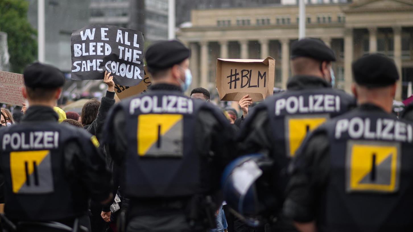 Während einer Kundgebung gegen Rassismus am 6. Juni in Stuttgart stehen Polizisten vor Demonstranten. Auf einem Transparent steht auf Englisch: "We all bleed the same colour" (Wir alle bluten in der gleichen Farbe).