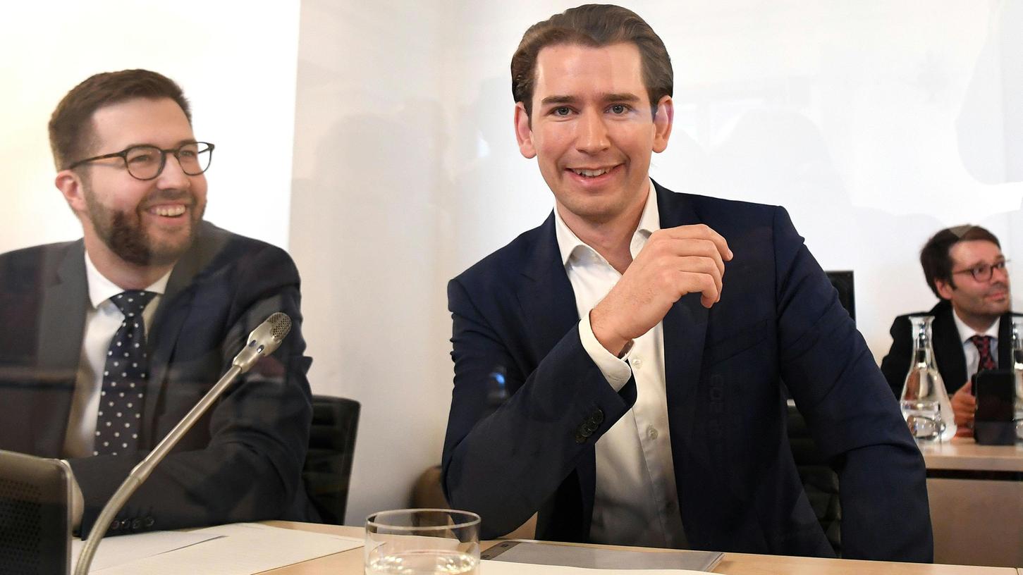 Neben der Vertrauensperson Lucas Weigerstorfer (links) sitzt Österreichs Bundeskanzler Sebastian Kurz (ÖVP) vor Beginn des Ibiza-Untersuchungsausschuss im Parlamentsausweichquartier in der Hofburg hinter einer Plexiglasscheibe und lächelt die Pressevertreter an.