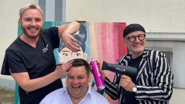 Benefiz-Haarschneiden von Friseur Marcel Schneider (li.) mit Kabarettist Oliver Tissot (re.) und Sänger Alexander Herzog (sitzend).