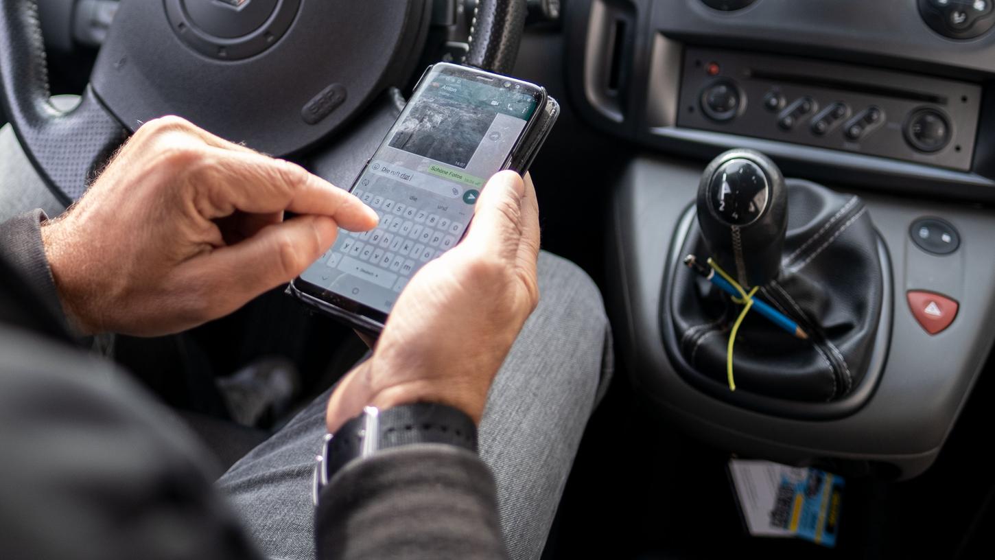 Nachrichten tippen am Handy und dabei Autofahren (Symbolbild), da wird ein Bußgeld fällig. 