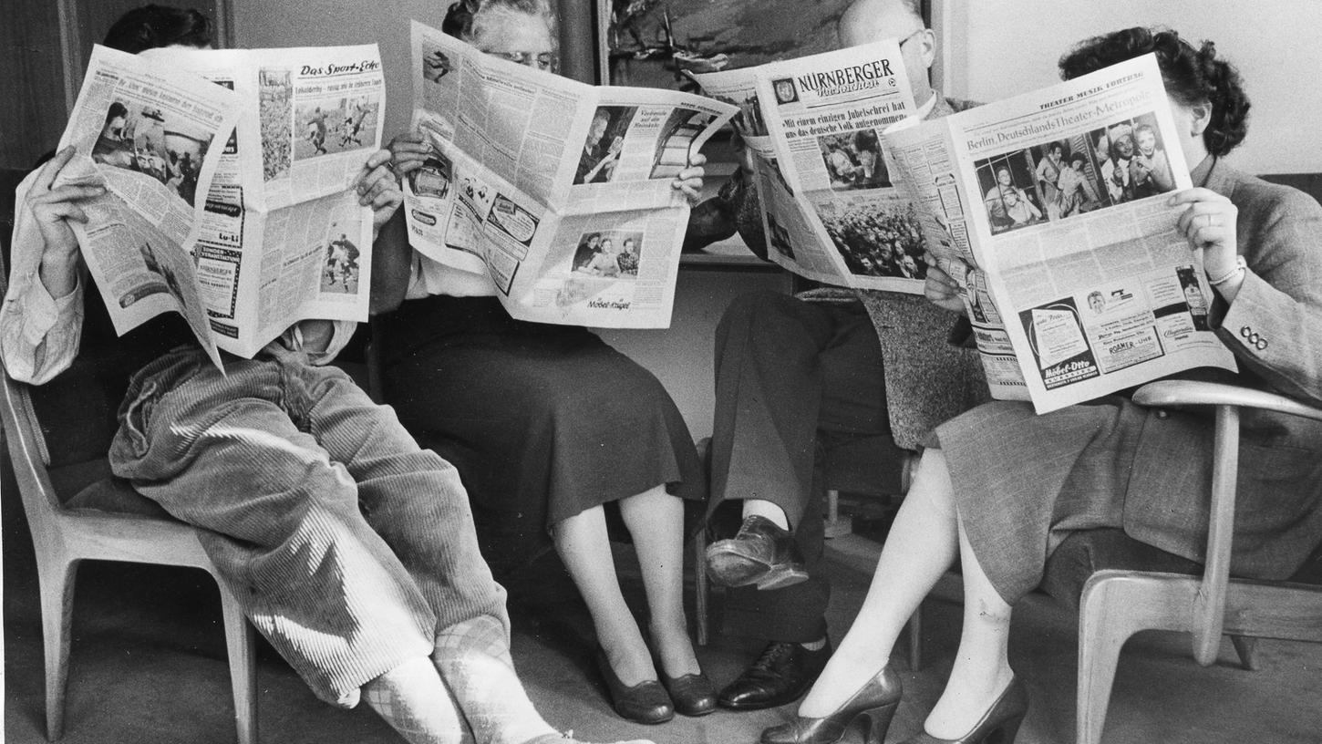 Ganz vertieft in Ihre Zeitung: Leserinnen und Leser im Jahr 1955 bei der Lektüre der Nürnberger Nachrichten.