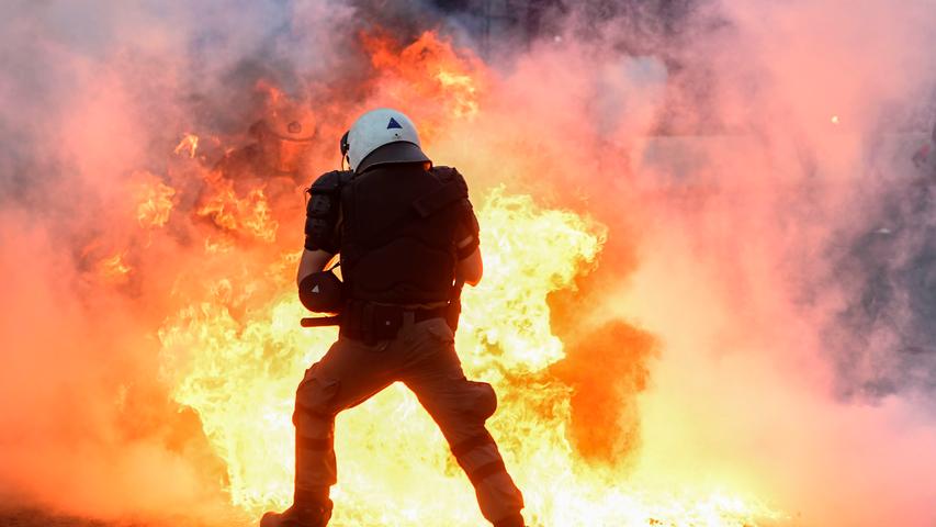 Ein Polizist rennt in der griechischen Hauptstadt Athen an brennenden Barrikaden vorbei, die Demonstranten errichtet und angezündet hatten. Sie protestierten unter anderem gegen eine umstrittene Verschärfung des Versammlungsrechts, 