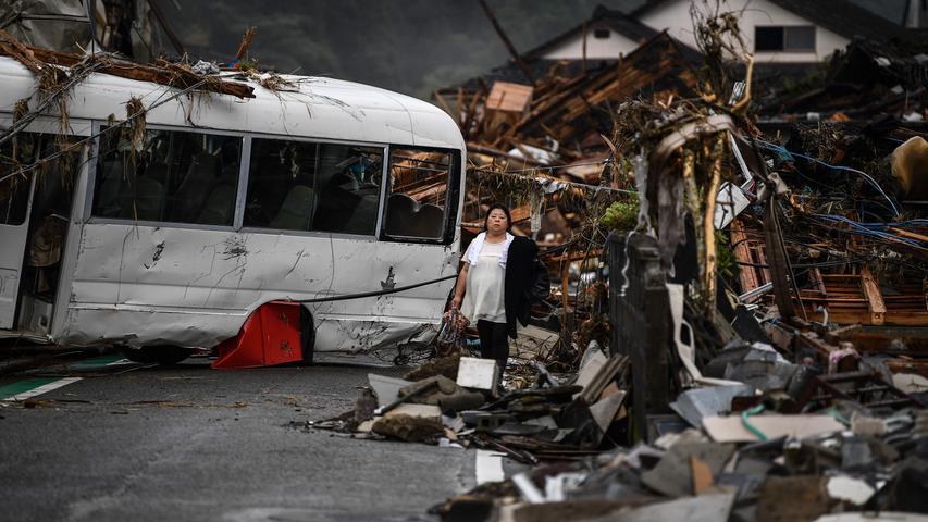 Eine Japanerin steht in Hitoyoshi (Präfektur Kumamoto) zwischen Trümmern und einem demolierten Bus: Heftige Regenfälle und anschließende Überschwemmungen hatten in Teilen des Landes schwere Verwüstungen angerichtet. Es gab mehrere Dutzend Tote zu beklagen.