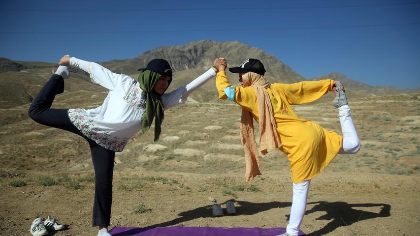 Afghanische Frauen stehen anlässlich des Welt-Yoga-Tages am Rande von Kabul auf einer Matte und machen eine Yogaübung. Weltweit taten es ihnen Millionen Yoga-Anhänger gleich.