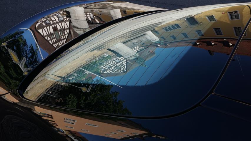Ein Auto als Spiegel im Zentrum von Heilsbronn. Man erkennt das Rathaus und den Katharinenturm.