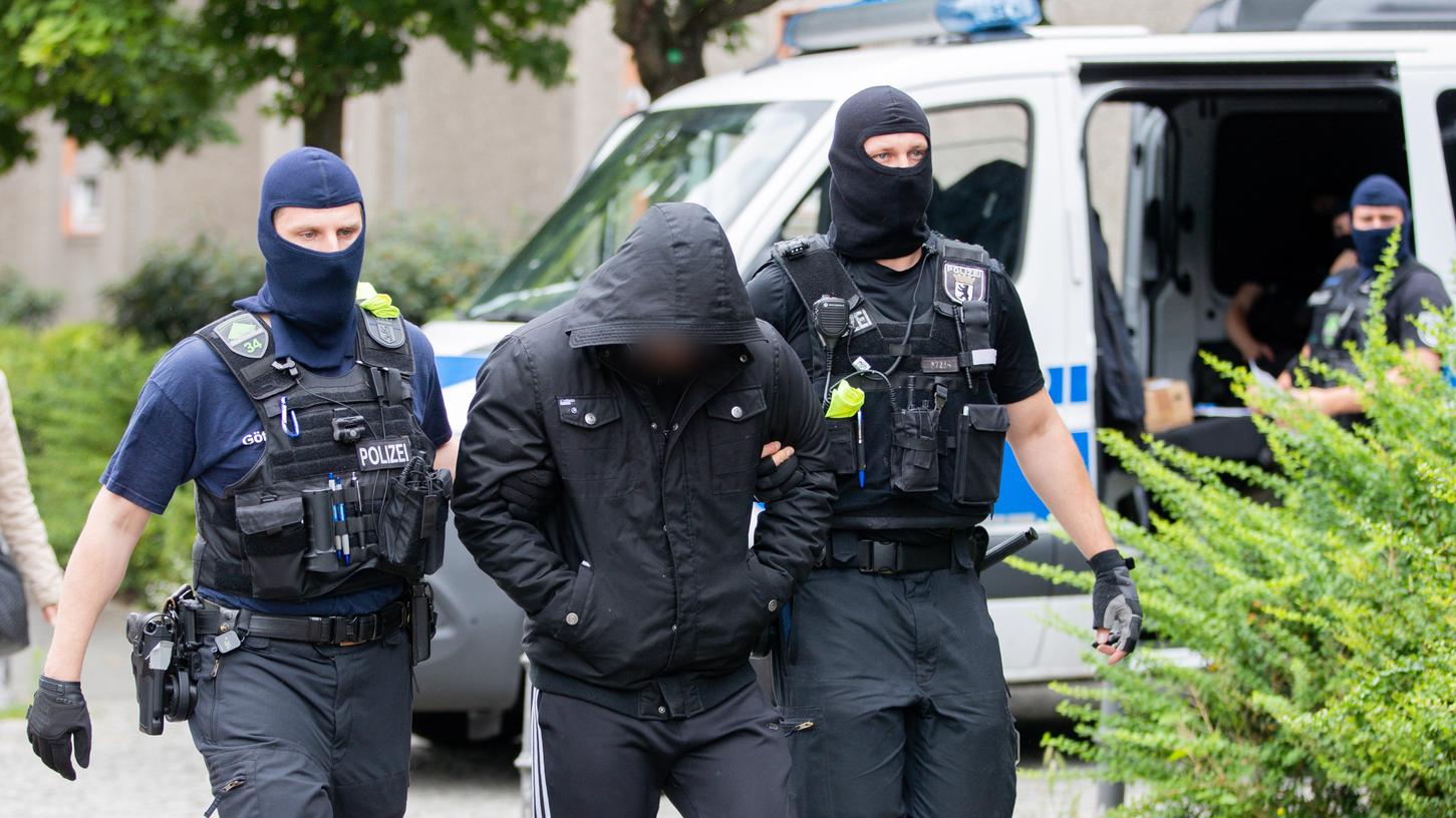 Ein Mann wird bei einem Polizeieinsatz im Rahmen einer groß angelegten Razzia gegen Tatverdächtige aus der islamistischen Szene in Berlin-Gesundbrunnen von zwei Polizisten abgeführt.