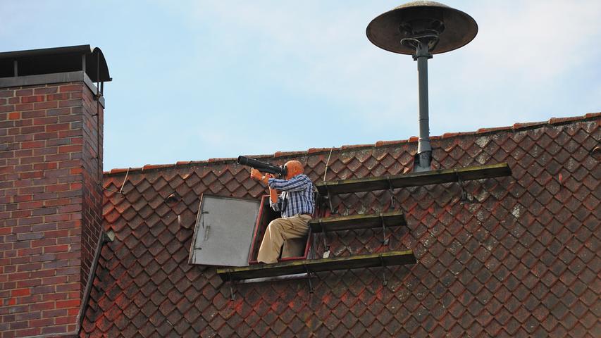 Ein Bergsteiger hat keine Höhenangst, also kann er auch locker vom Rathausdach die Störche fotografieren.
  