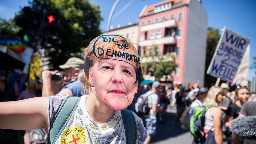 01.08.2020, Berlin: Eine Frau trägt eine Merkel-Maske mit der Aufschrift «Bye bye Demokratie» auf der Demonstration gegen die Corona-Beschränkungen. Zu der Demonstration gegen die Corona-Maßnahmen hat die Initiative «Querdenken 711»  aufgerufen. Das Motto der Demonstration lautet «Das Ende der Pandemie - Tag der Freiheit». Foto: Christoph Soeder/dpa +++ dpa-Bildfunk +++