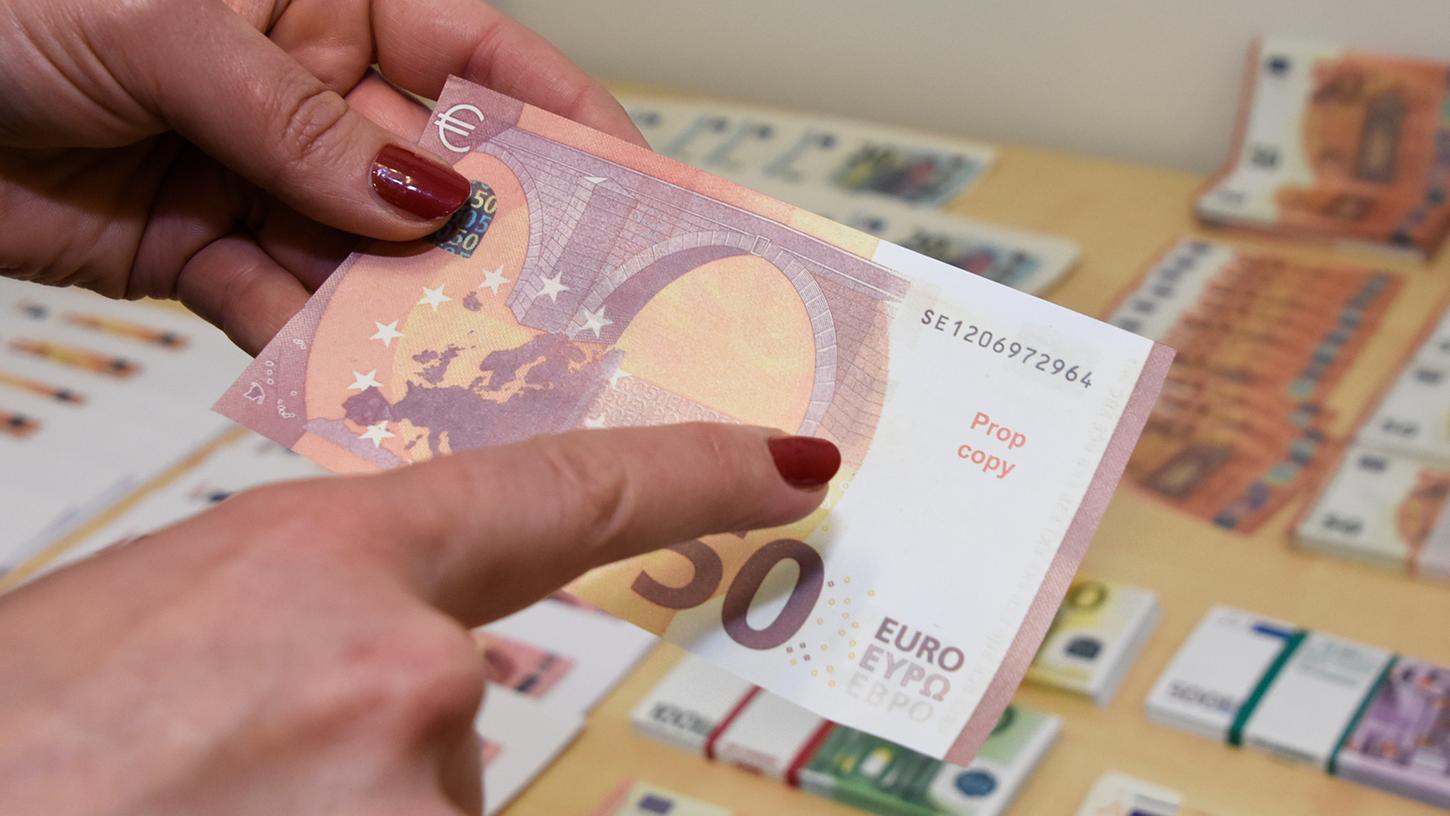 Eine Mitarbeiterin des bayerischen Landeskriminalamts zeigt einen gefälschten Geldschein, der im Landkreis Freising beschlagnahmt worden war.