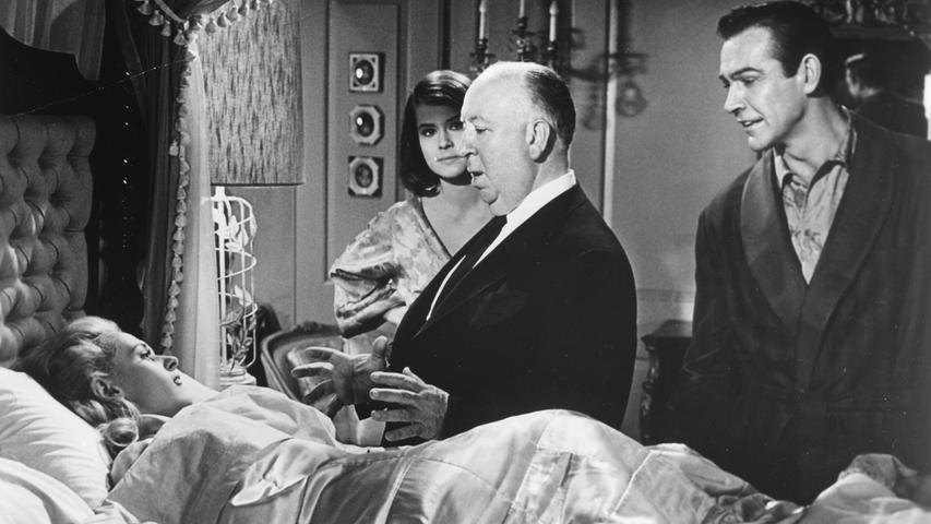 Große Leinwanderfolge feierte Sean Connery schon während seiner Bond-Zeit auch mit anderen Filmen: Hier ist er 1964 bei Dreharbeiten zu "Marnie" mit Regisseur Alfred Hitchcock und Filmpartnerin Tippi Hedren (im Bett) zu sehen. 