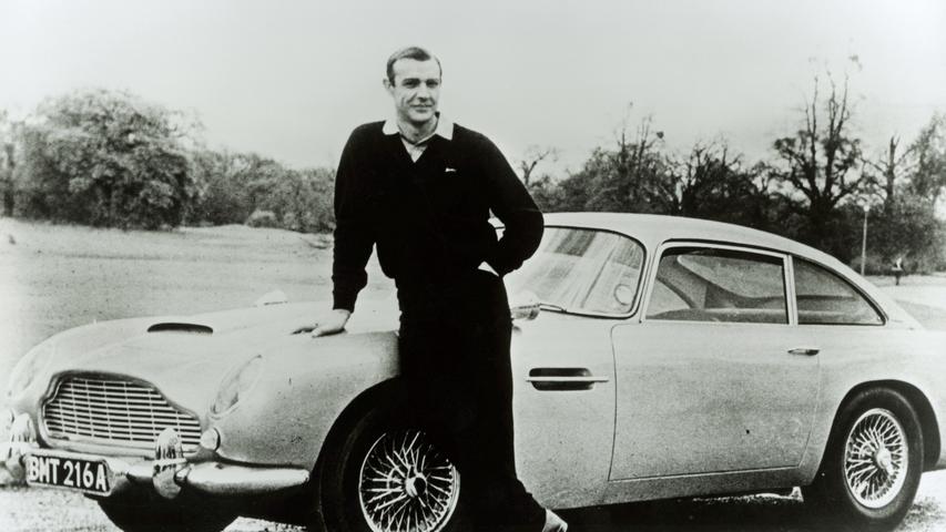 Sean Connery mit dem wohl berühmtesten Bond-Auto, einem Aston Martin DB5, der durch die Filme "Goldfinger" und "Feuerball" populär wurde und wegen seines Kultstatus' ab den 1990er Jahren erneut in der 007-Reihe eingesetzt wurde. 
