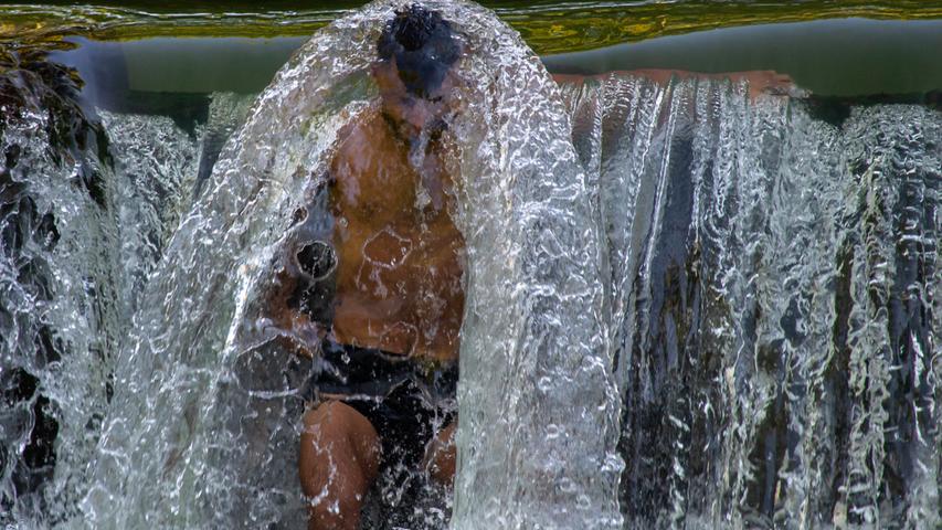 Heiß geht es auch in Bayern zu. Die Temperaturen stiegen auf bis zu 35 Grad Celsius, nachts gab es kaum Abkühlung. Im Englischen Garten in München sah ein Mann nur noch eine Chance auf Erfrischung: unter einem Wasserfall.
