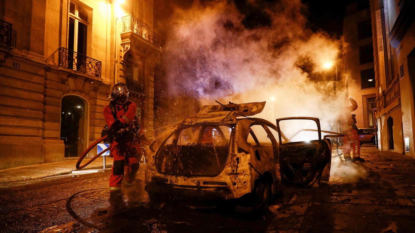 Feuerwehrmänner löschen ein brennendes Auto in der Nähe der Champs-Elysées. 