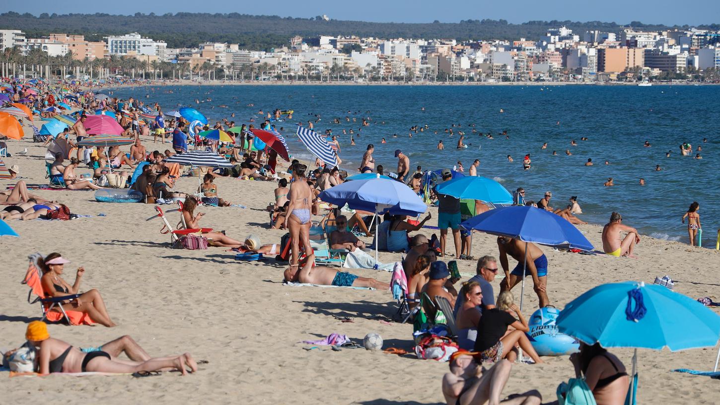 Spanien, Palma de Mallorca: Menschen genießen die Sonne am Strand von El Arenal. Während Lokale an Partymeilen auf Mallorca geschlossen wurden, waren die Strände bis jetzt weiter offen.