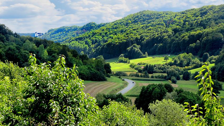 Schöne Ausblicke gibt es viele in der Fränkischen Schweiz. Hier eine stimmungsvolle Aussicht mit sonnenbeschienenen Wiesenhängen und Wäldern und der Egloffsteiner Burg am Horizont. Aufgenommen von einer Anhöhe über dem Trubachtal.