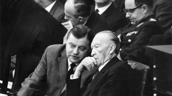Bundesverteidigungsminister Franz Josef Strauß (links) unterhält sich im Bundestag mit Bundeskanzler Konrad Adenauer (CDU) während der dritten Spiegel-Debatte im November 1962. Im Spiegel erschien der Artikel "Bedingt abwehrbereit" von Conrad Ahlers, Strauß ordnete Ermittlungen an. Die Verlagsräume der "Spiegel"-Redaktionen in Hamburg und Bonn wurden durchsucht, "Spiegel"-Herausgeber Rudolf Augstein und Chefredakteur Claus Jacobi wegen Landesverrats verhaftet. Anfangs wurde Strauß in der Spiegel-Affäre noch von Adenauer gedeckt; nach dem geschlossenen Rücktritt der FDP-Minister am 19. November 1962 war Strauß am 30. November 1962 gezwungen, von seinem Amt als Verteidigungsminister zurückzutreten. Adenauer bildete am 14. Dezember 1962 ein neues Kabinett mit der FDP und ohne Strauß.