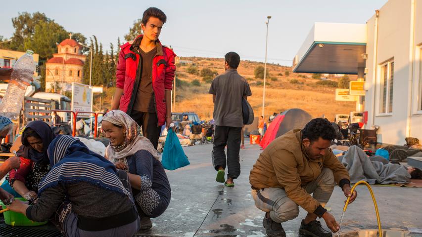 Menschen waschen sich an einer Tankstelle in der Nähe des ausgebrannten Flüchtlingslagers Moria. 