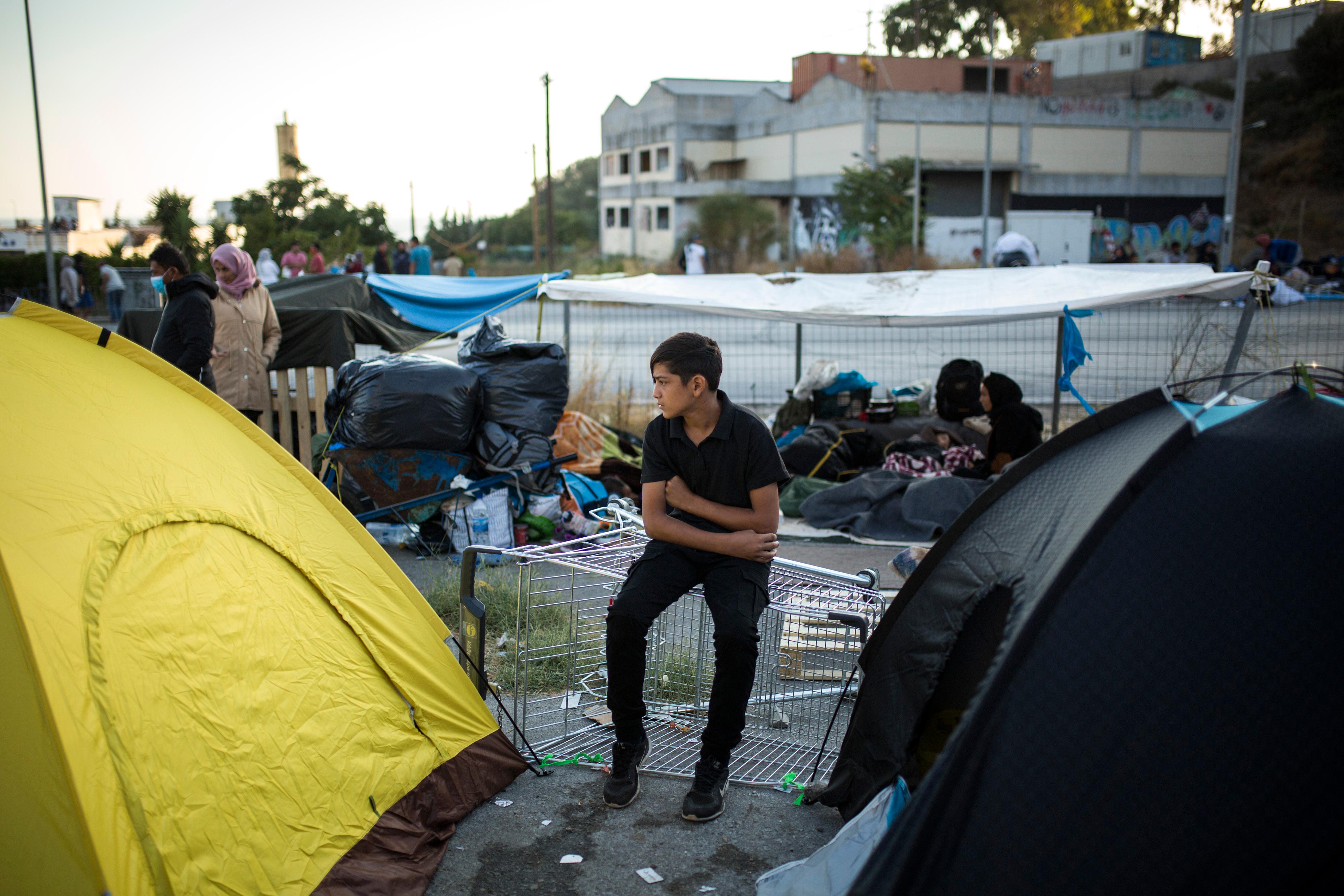 Ein Kind sitzt am Rande einer Straße zwischen zwei Zelten. Die Situation war schon vor dem Brand angespannt - nun sind die Menschen noch mittelloser. 